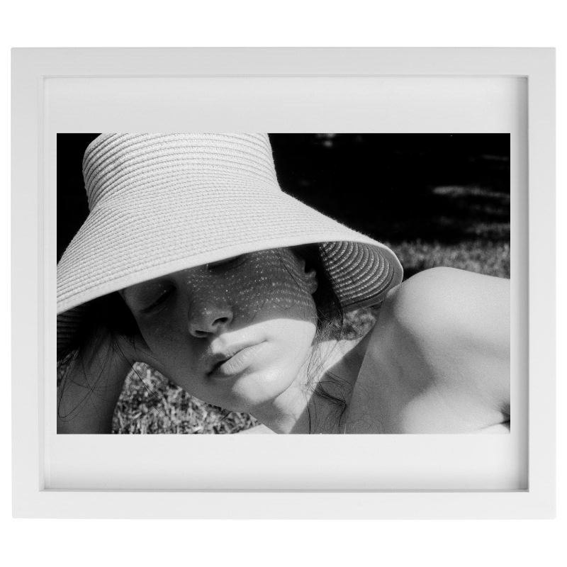 Photograph of a woman laying on the beach in a white frame