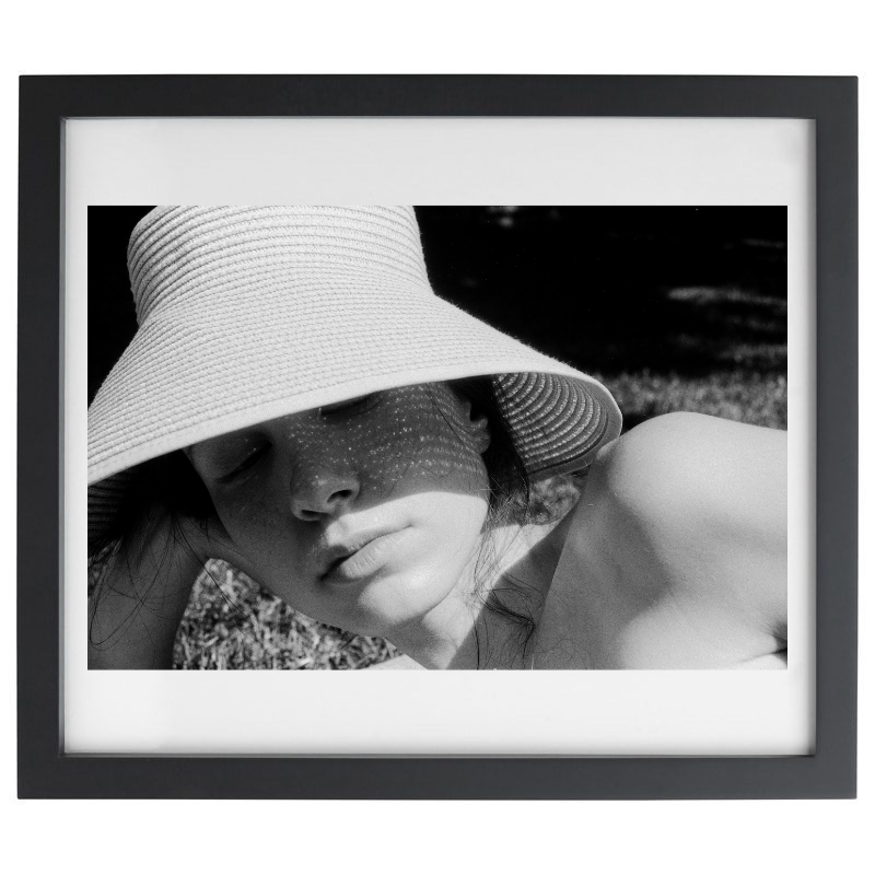 Photograph of a woman laying on the beach in a black frame