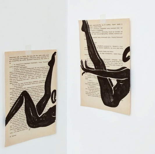 Minimalist artwork of a female form on top of a page of a book pictured on the wall